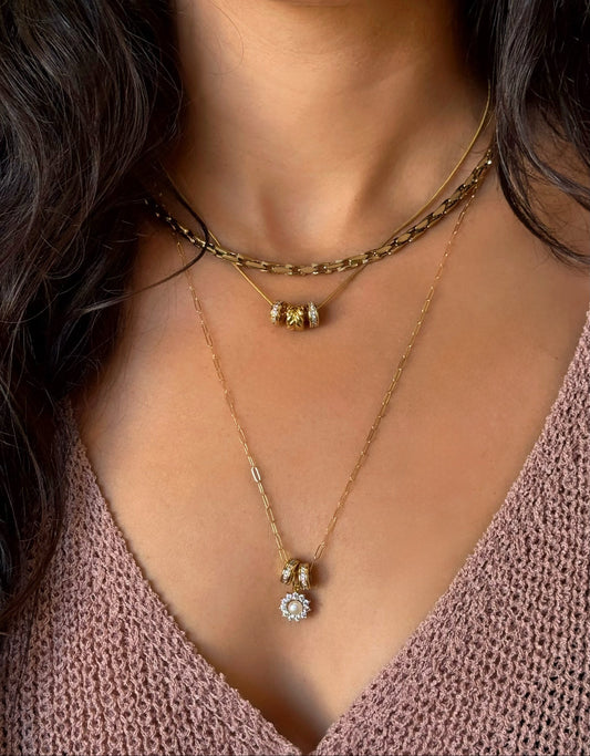 Close-up of a person wearing gold necklaces with a soft focus on the face.